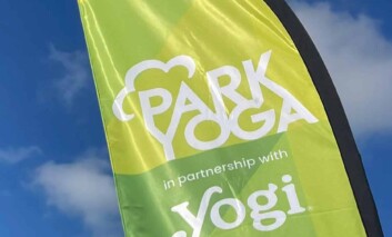A green Park Yoga flag flies against a blue sky