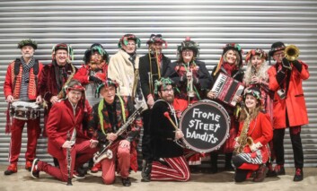 A big brass band standing in front of a metal shutter.