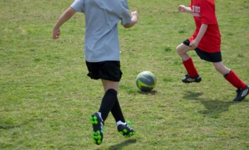 Two children kicking a football on grass