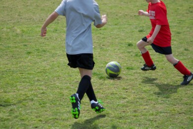 Two children kicking a football on grass