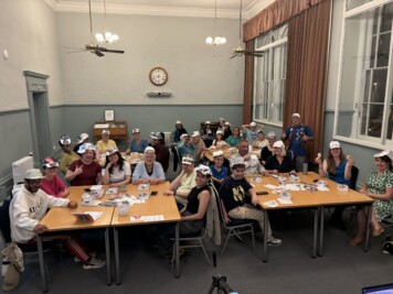Origami workshop showing attendees with their folded baseball caps