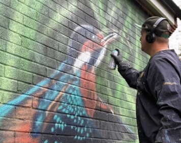 Mr Sce spray painting the new kingfisher mural